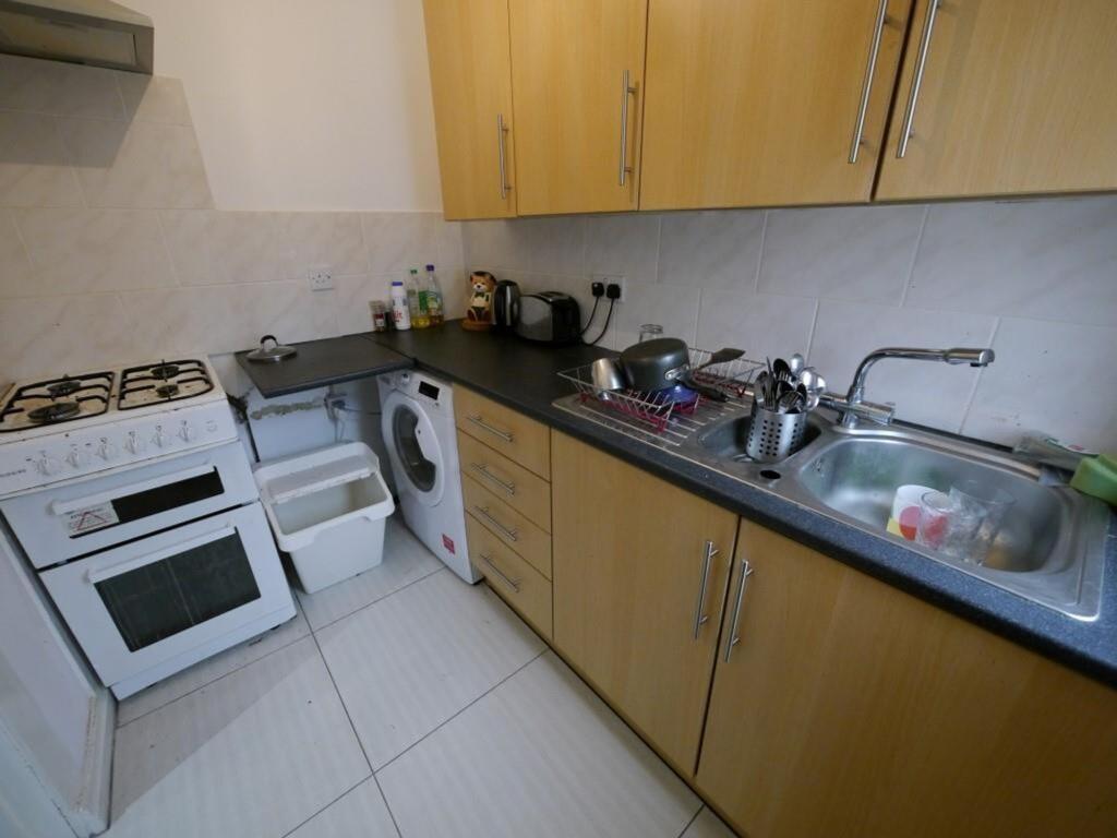 A compact kitchen featuring wooden cabinetry, a...