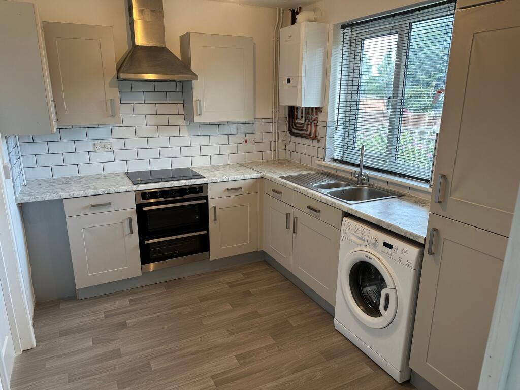 A bright, modern kitchen featuring marble-effec...