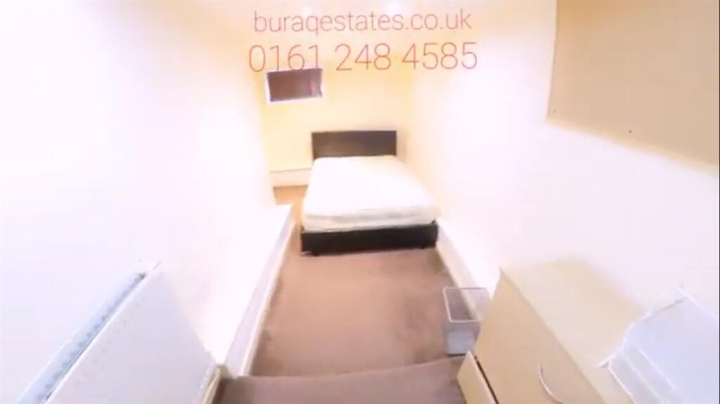 A narrow, tidy room with a single bed and basic...