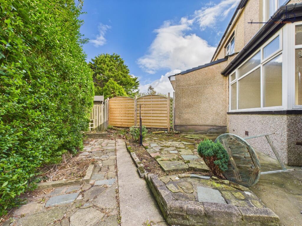 Wrap around garden to the side and the front with mature plant beds, flags and lawn