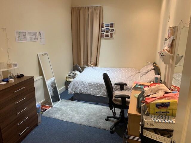 A cozy single bedroom featuring a bed, a desk, ...