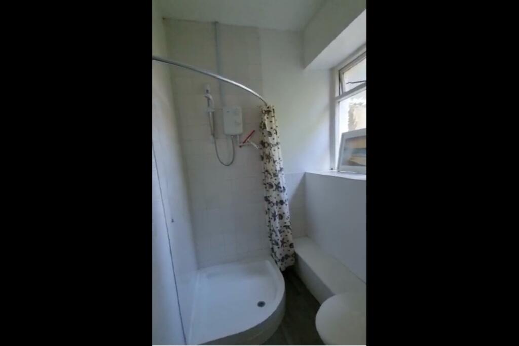 Bright bathroom featuring a corner shower with ...