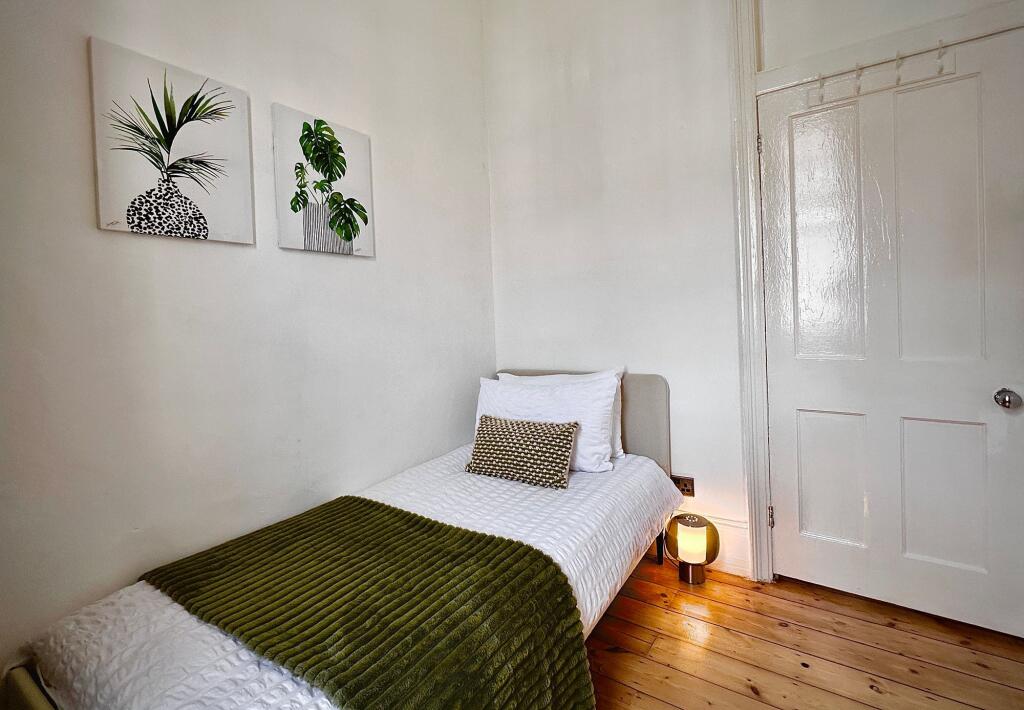 A cozy single bedroom featuring a neatly made b...