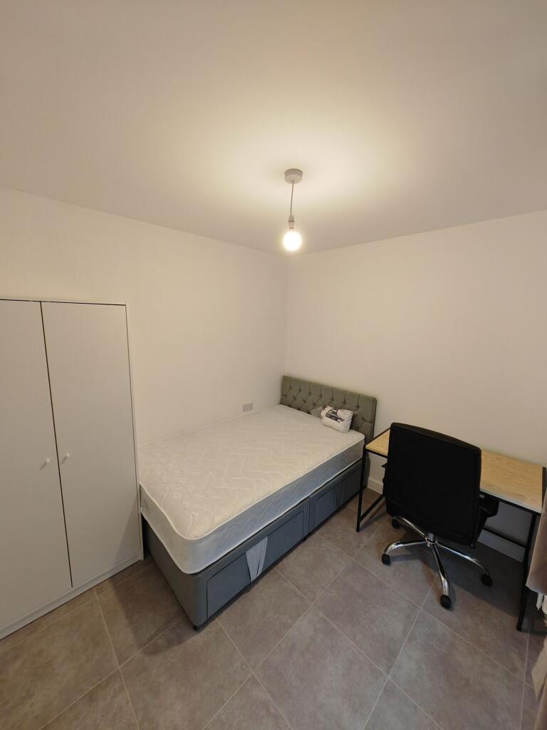 A neat and tidy single bedroom featuring a comf...