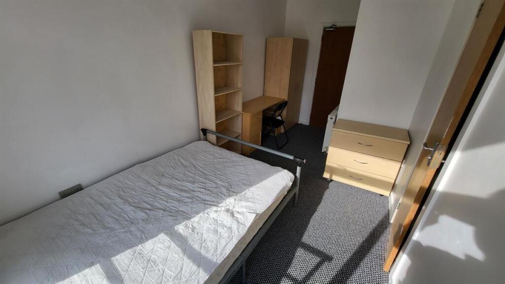 A bright single bedroom featuring a neatly made...