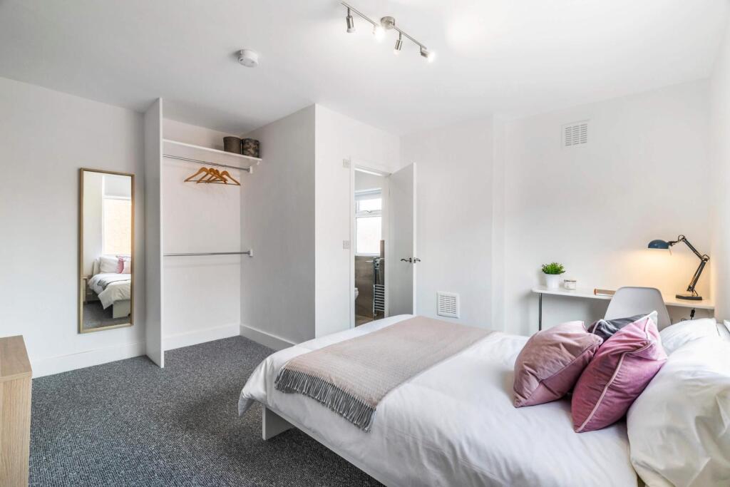 A bright, spacious master bedroom featuring a c...
