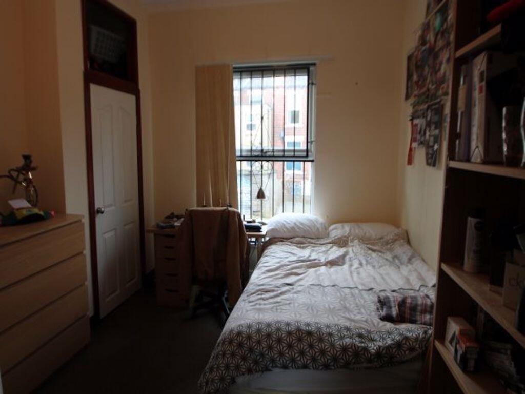 A cozy bedroom featuring a bed with a patterned...