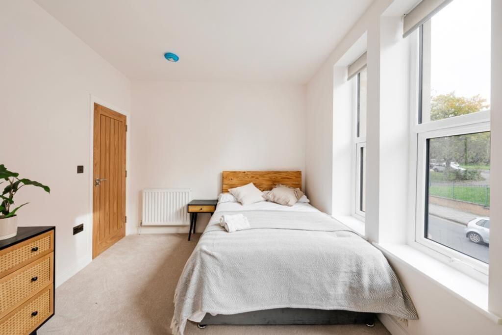 A bright and tidy double bedroom featuring larg...