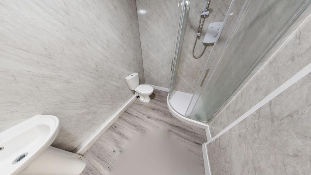 Compact bathroom featuring a modern corner show...