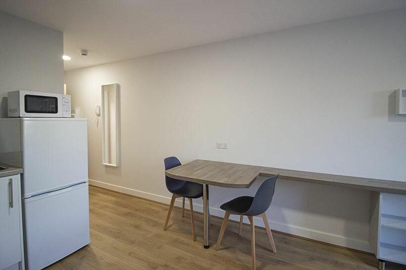 A clean, modern kitchen area featuring a fridge...
