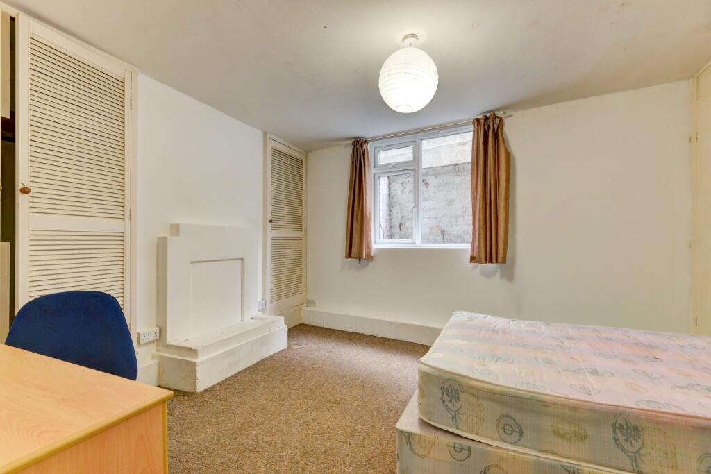 A simple, clean bedroom featuring a single bed ...