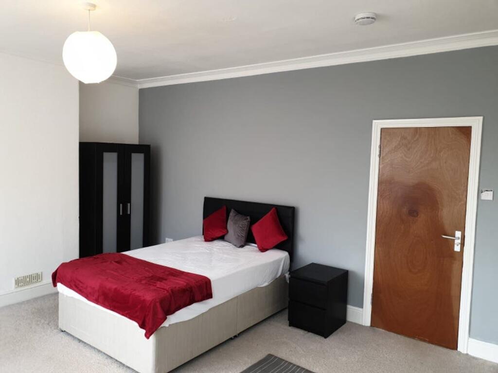 A tidy double bedroom featuring a bed with red ...
