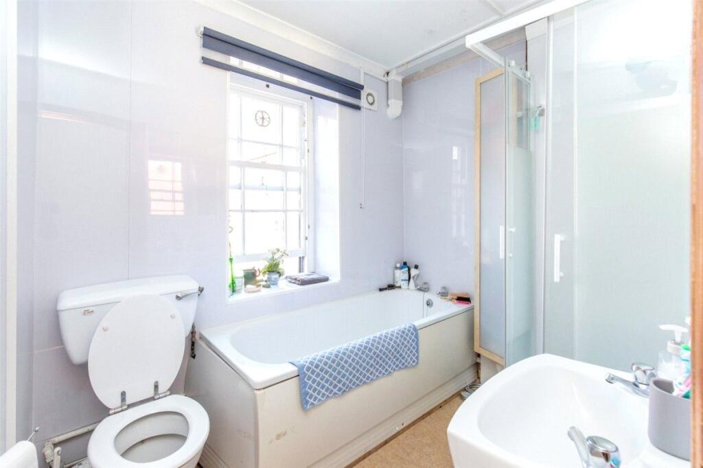 Bright and clean bathroom featuring a bathtub, ...