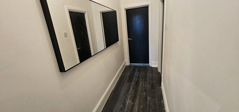 A clean and modern hallway with dark wood floor...