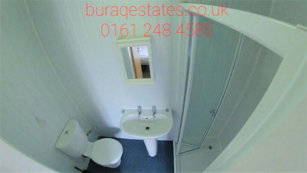 Compact bathroom featuring a clean white toilet...