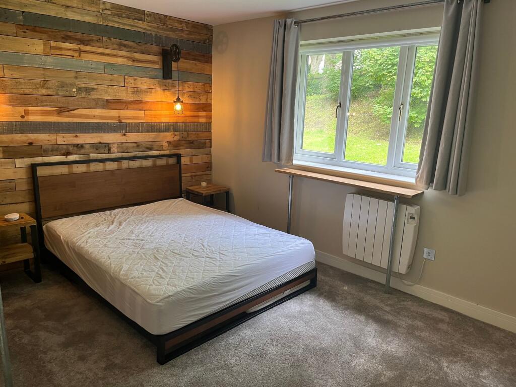 A cozy double bedroom featuring a stylish wood-...