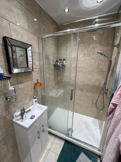 Well-presented tiled bathroom with a glass-encl...