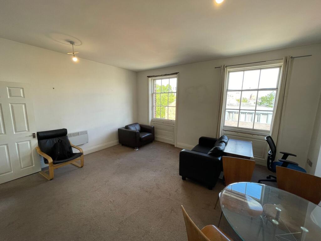A bright living room featuring two large sash w...