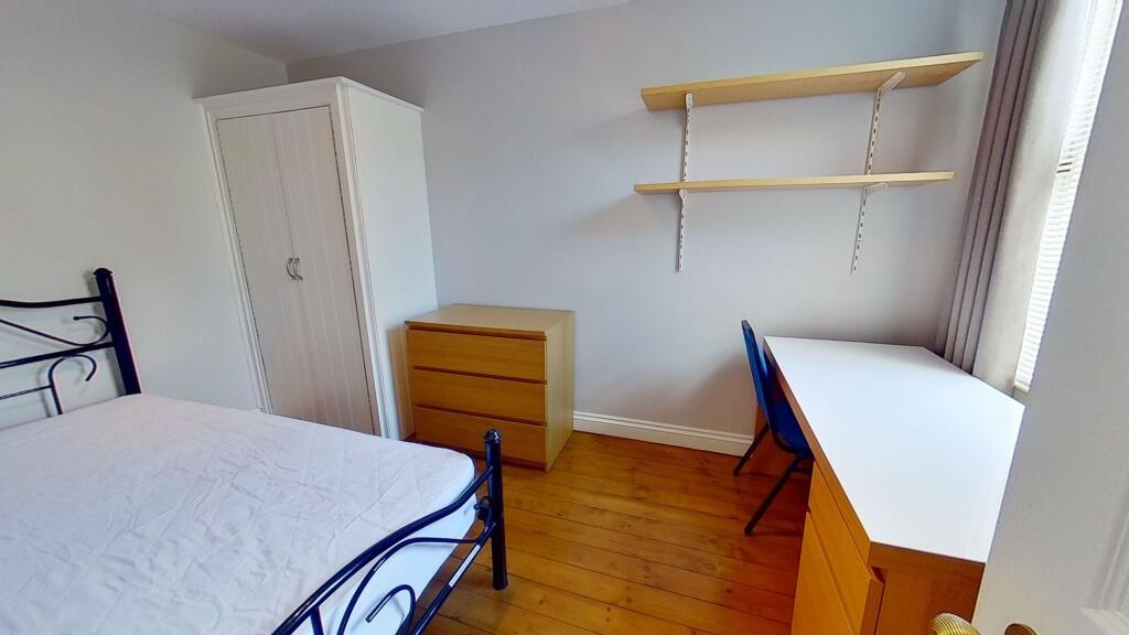 Bright, tidy bedroom with wooden floors, a meta...