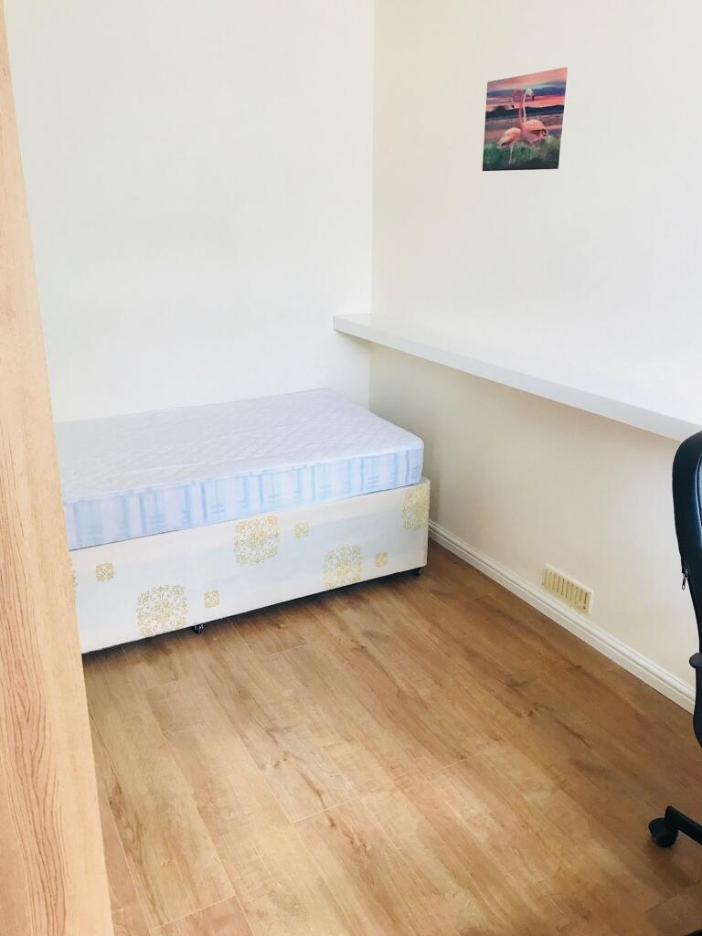 A small, tidy room featuring a single bed with ...