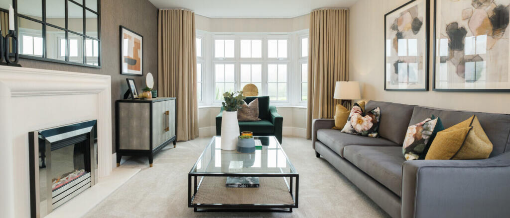 Modern living room with bay window, grey sofa with floral and mustard cushions, fireplace, and conte