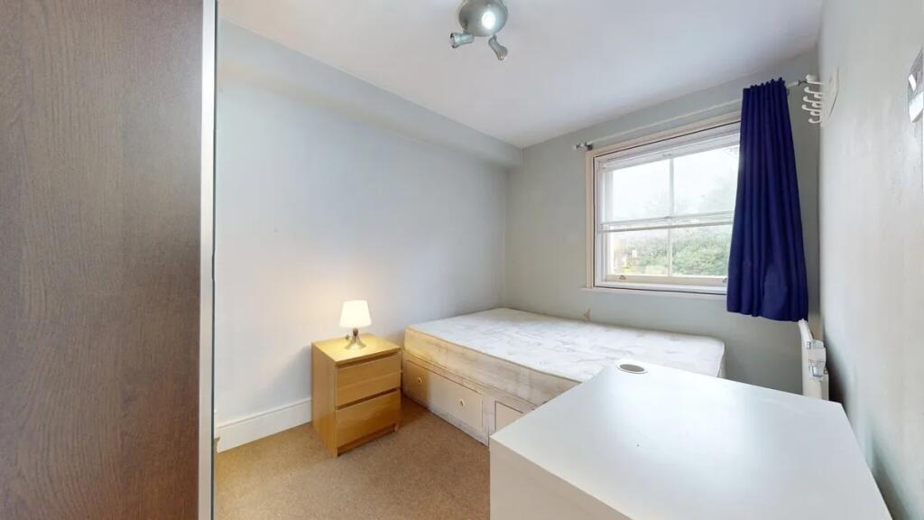 A neat and well-lit single bedroom featuring a ...