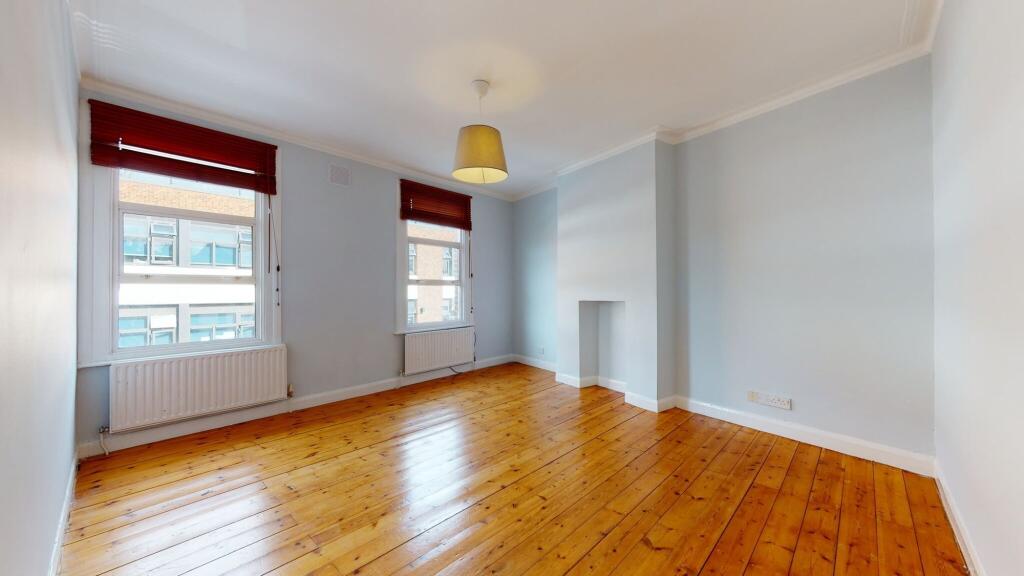 Bright double bedroom featuring polished wooden...