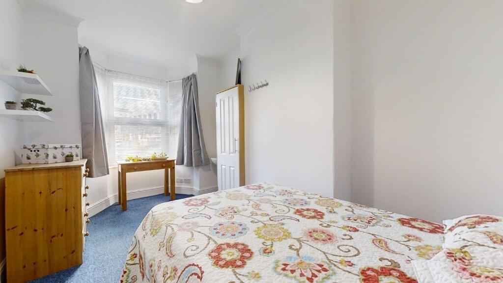 Bright single bedroom featuring a large window ...