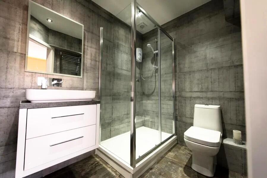 Modern bathroom featuring a sleek glass-enclose...