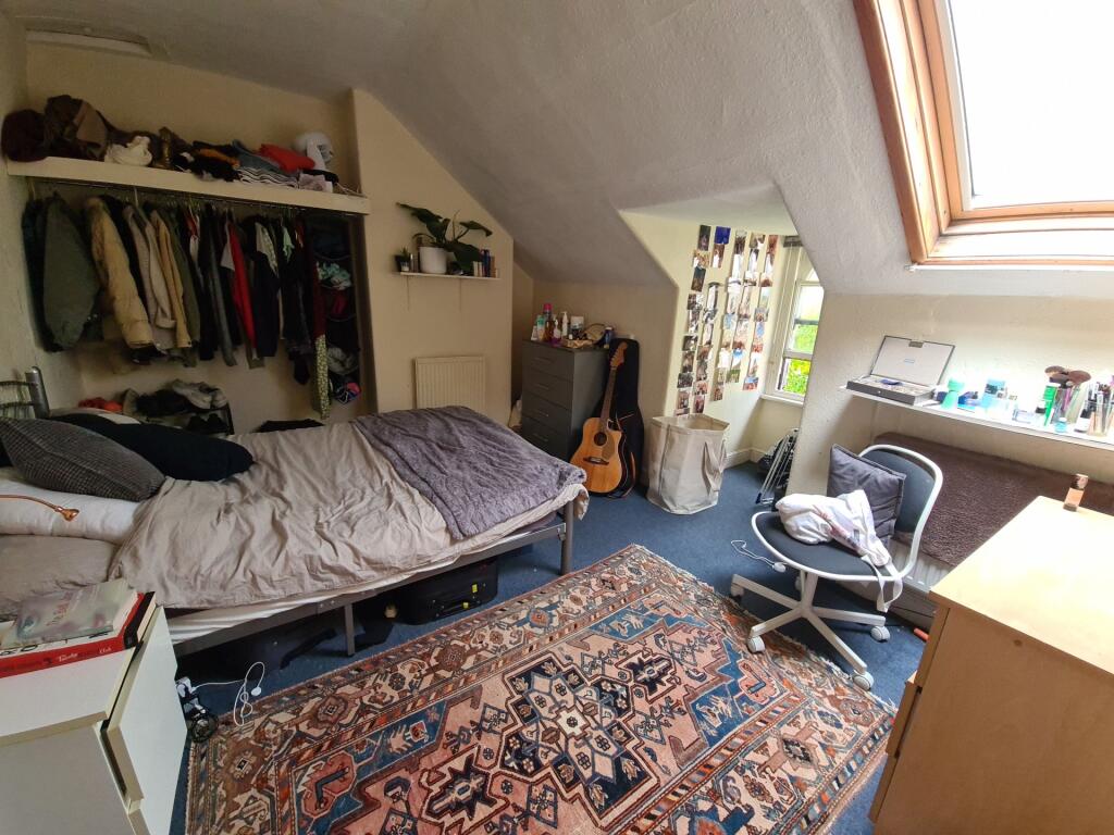 A cozy bedroom with a sloped ceiling and a skyl...