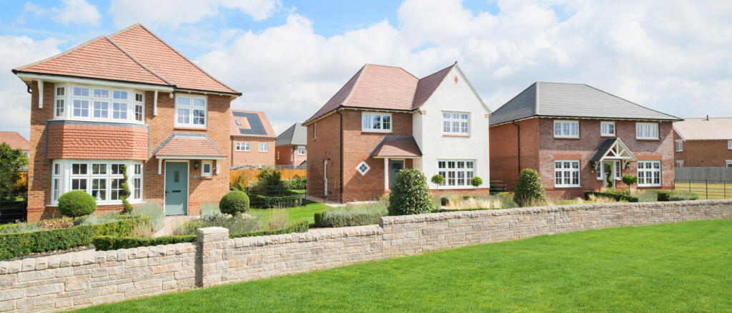 A row of newly built detached houses with brick and white external walls, surrounded by well-maintai