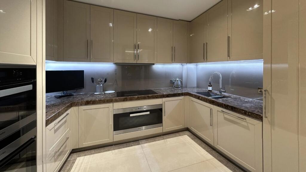 Modern kitchen featuring sleek beige cabinetry,...