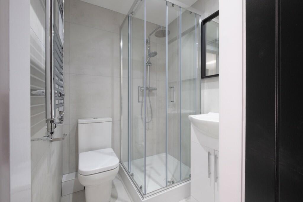 A modern bathroom featuring a sleek glass showe...