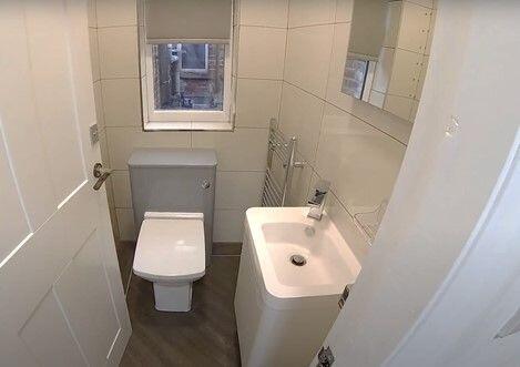 Bright, modern bathroom with white tiles, a con...