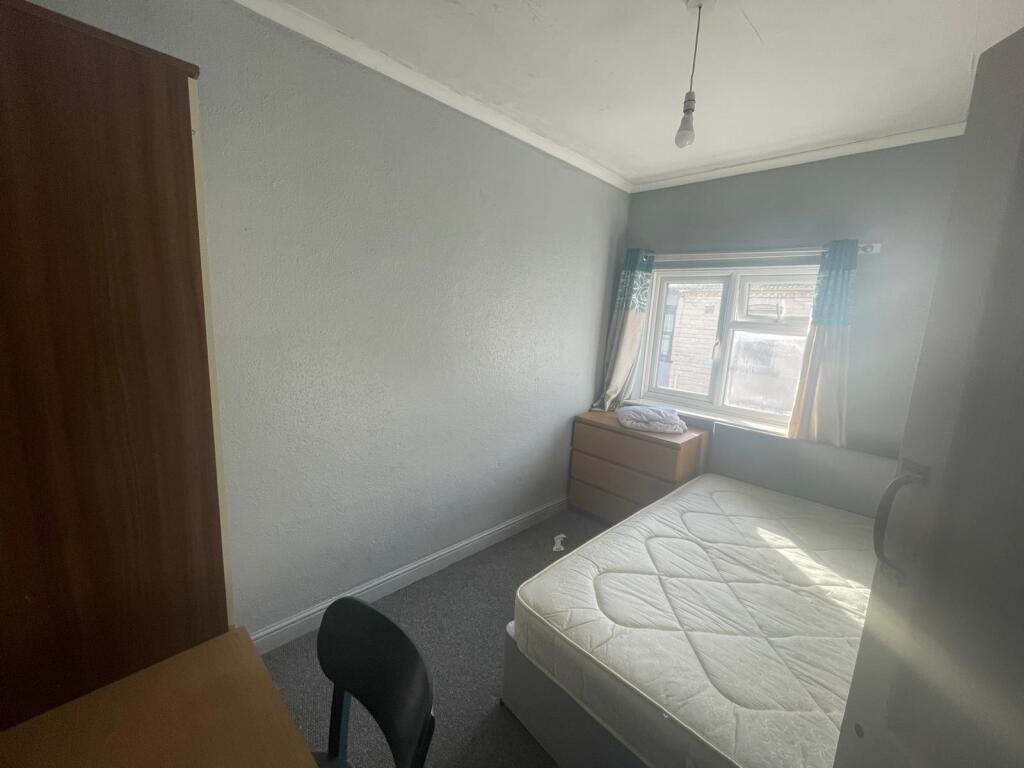 A modest-sized bedroom with a window allowing n...