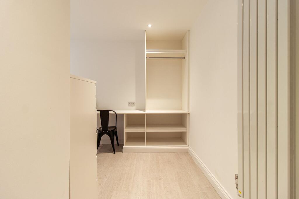 Neat, neutral single bedroom with built-in shel...