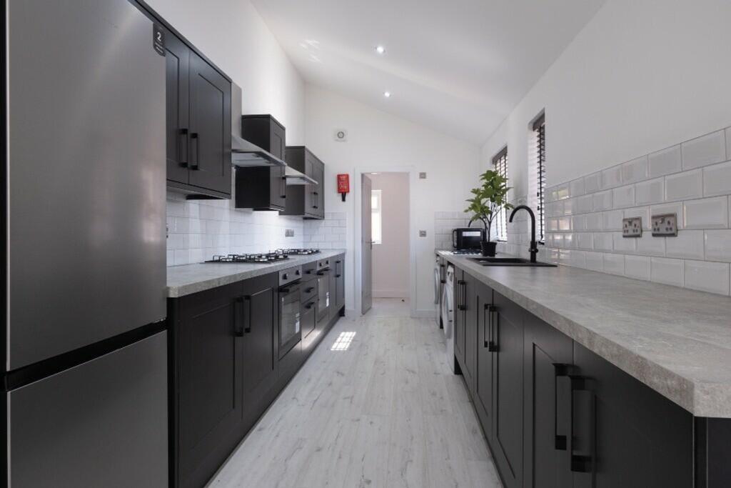 Modern kitchen featuring sleek black cabinetry,...
