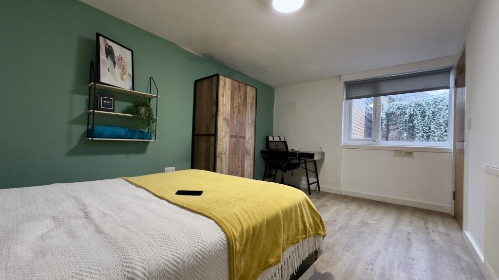 A bright and welcoming bedroom featuring a comf...
