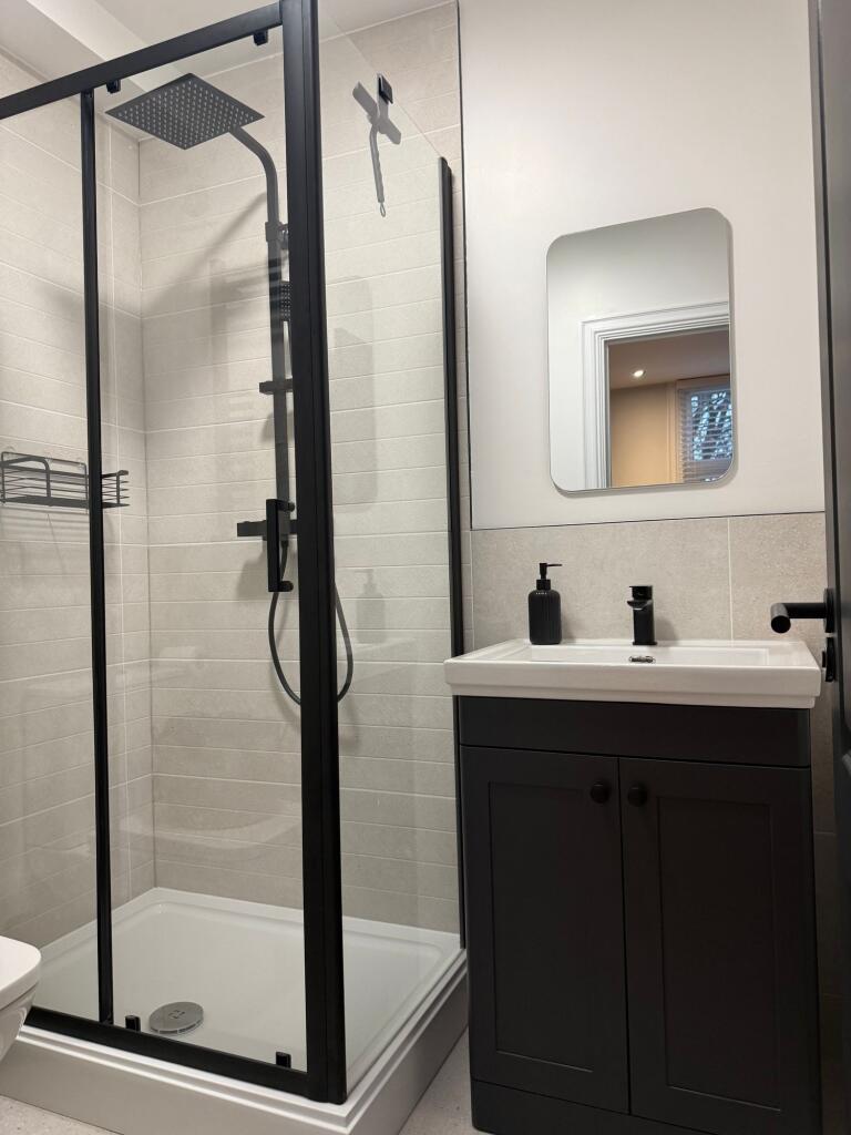A modern bathroom featuring a sleek black-frame...