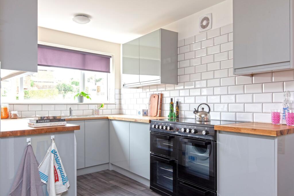 This modern kitchen features sleek cabinetry, a...