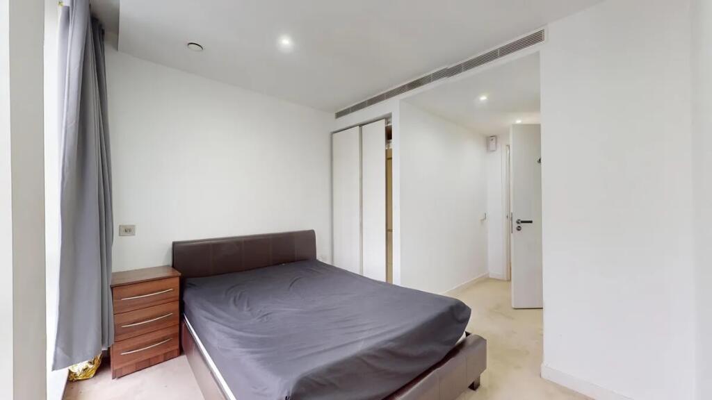 A clean and modern double bedroom featuring a c...