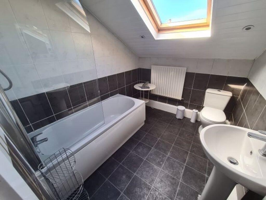 Bright and modern bathroom featuring a bathtub,...