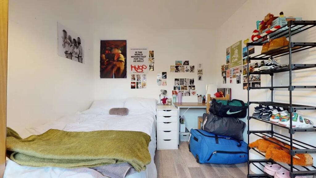 A cozy single bedroom featuring a neatly made b...