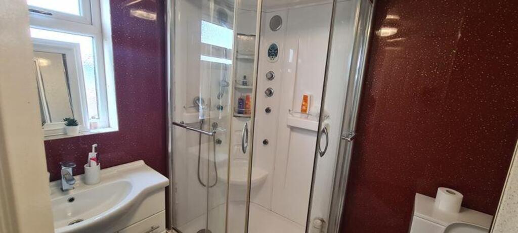 A modern bathroom featuring a spacious shower a...