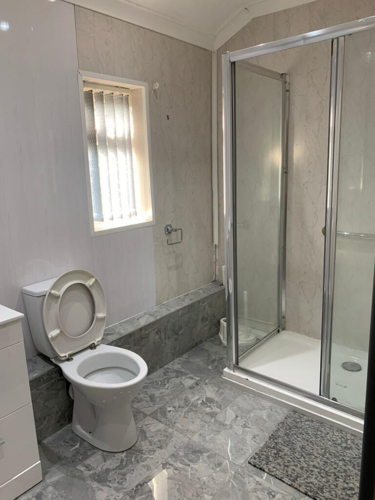 A modern bathroom featuring a glass-enclosed sh...