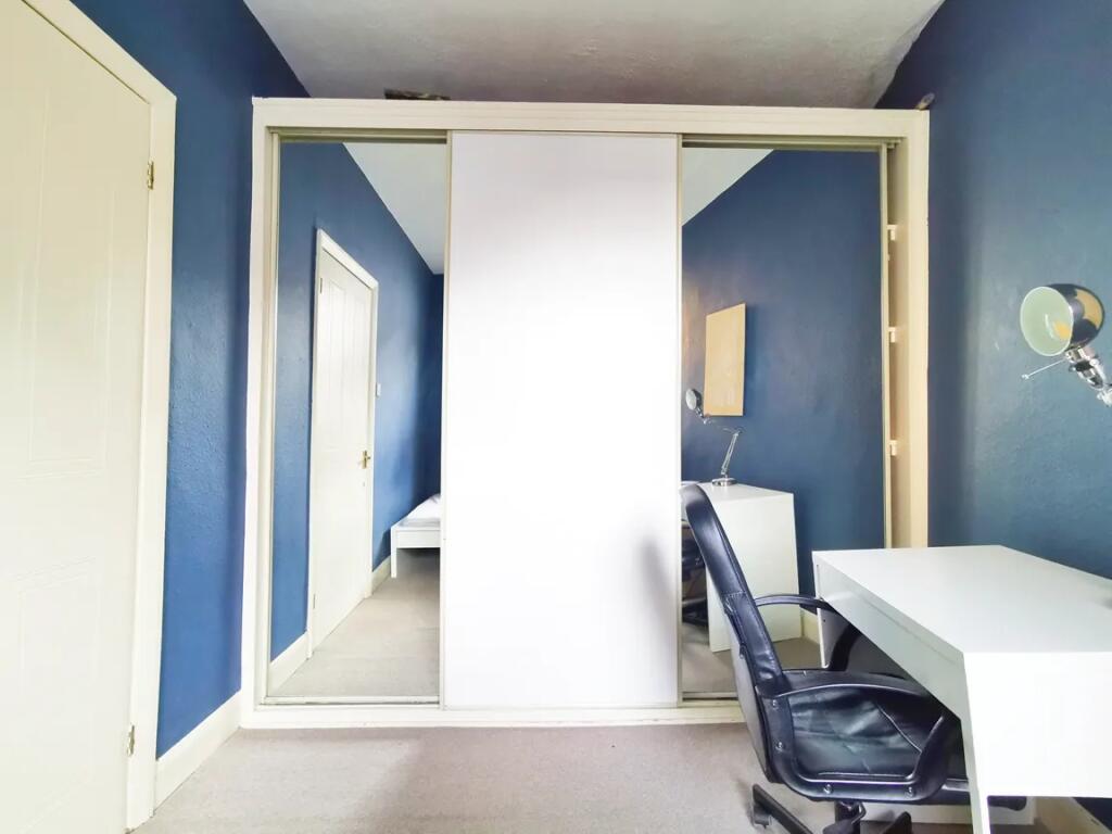 A tidy bedroom with deep blue walls, featuring ...