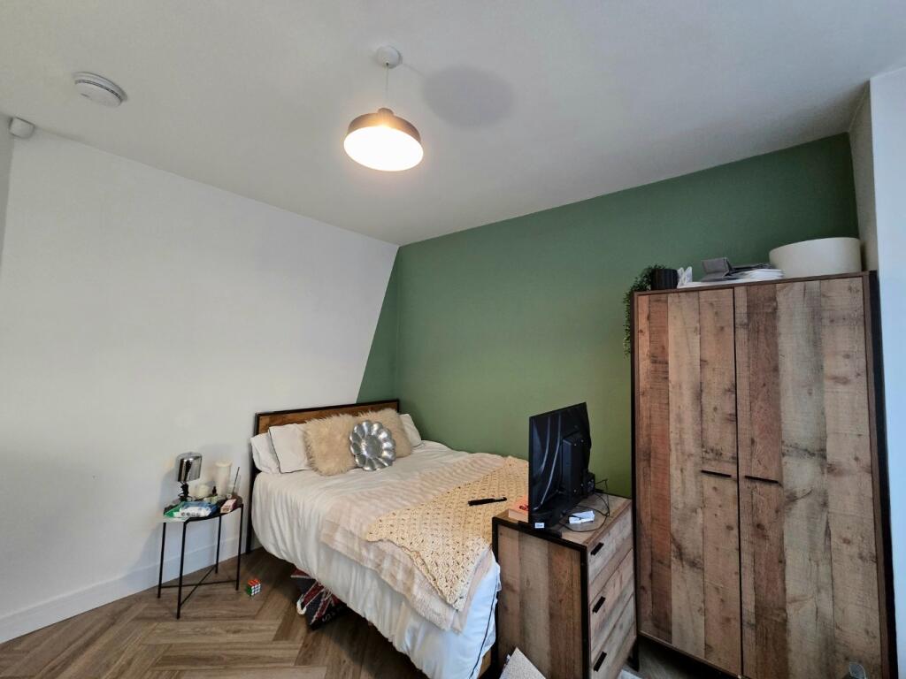 A cozy bedroom featuring a double bed, a bedsid...