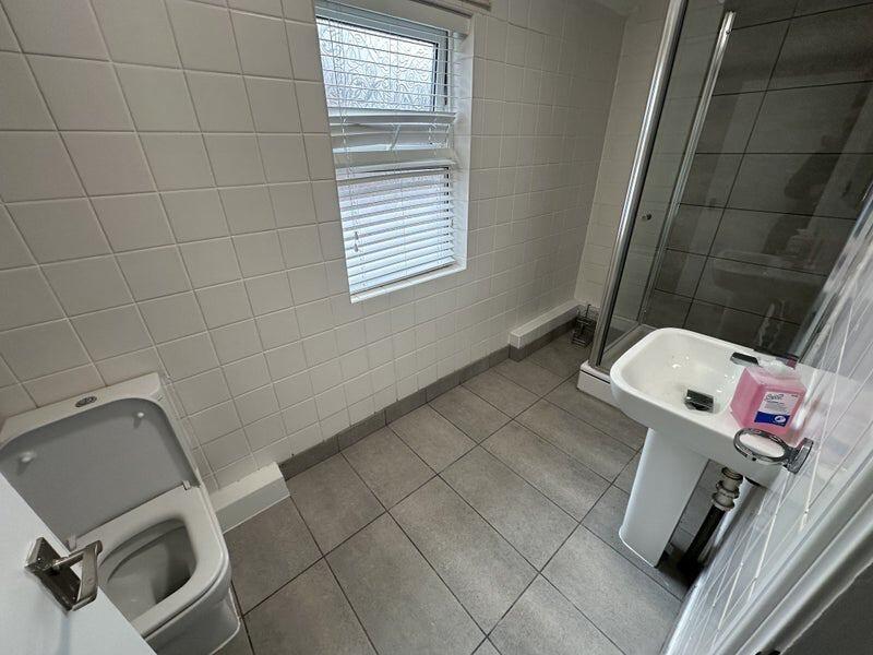 A modern bathroom featuring a clean white tiled...