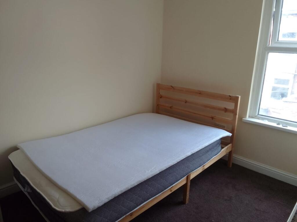 A simple and tidy bedroom featuring a wooden be...