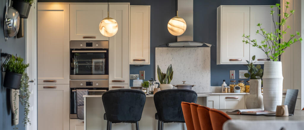 Modern kitchen with white cabinets, dark blue walls, and a marble backsplash, decorated with plants